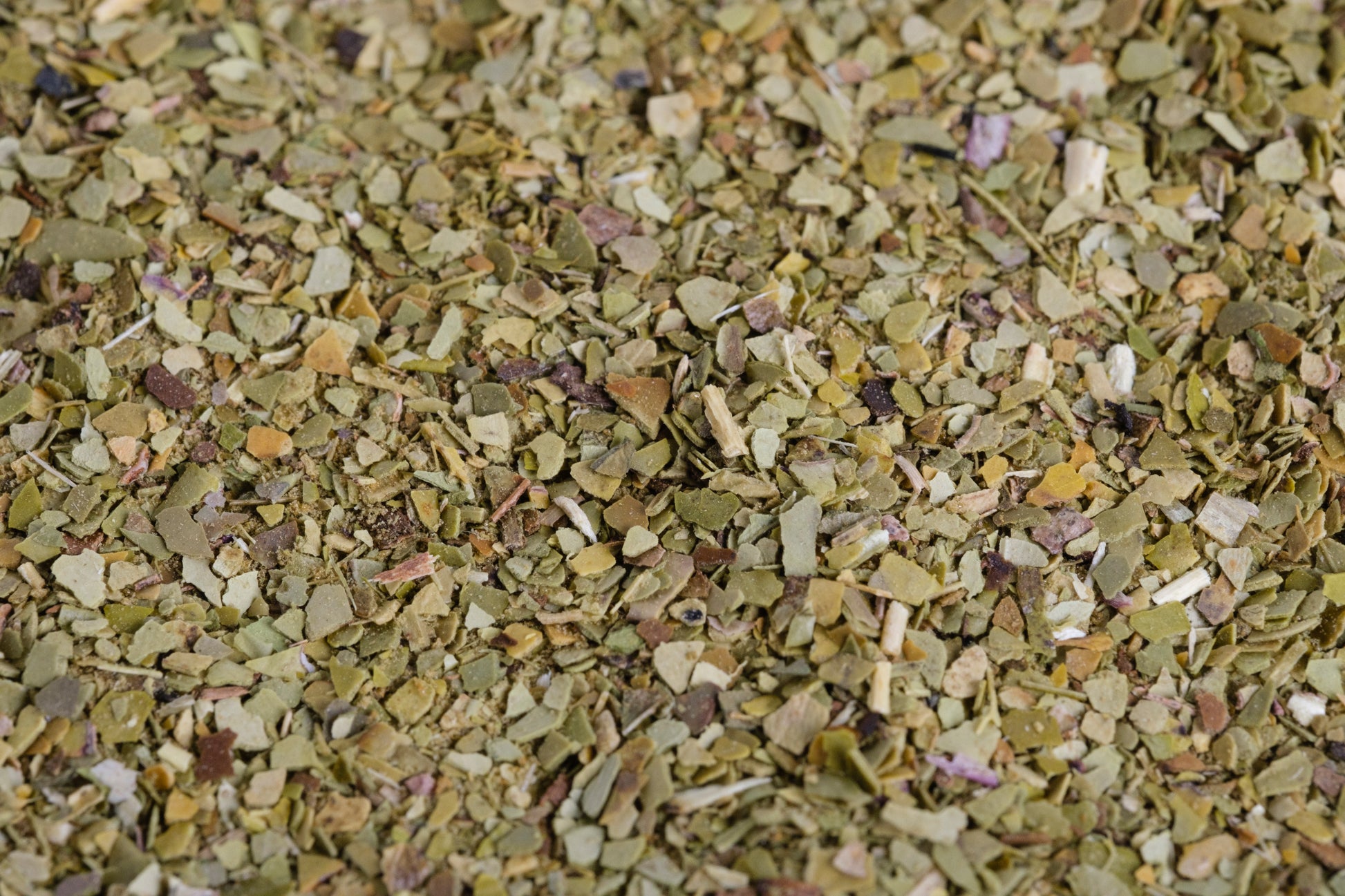 Extreme close-up of Yerba Montana Cafe Blend ground mate, green, white, brown, and tan bits

